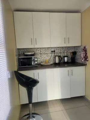 a kitchen with white cabinets and a black stool at MorningMist Boutique Sun in Centurion