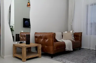 a brown leather couch in a living room with a table at Urbane- By LaSerene -Carlswald in Midrand