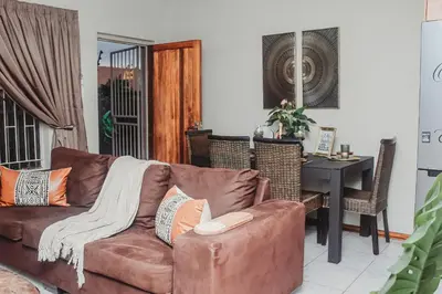 a living room with a brown couch and a table at Villa La'Vie in Witbank