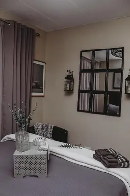 a room with a bed with a table and a mirror at Villa La'Vie in Witbank