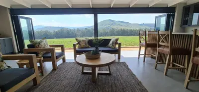a living room with a table and chairs and a large window at Highland gate Golf estate Mountain view 780 in Dullstroom