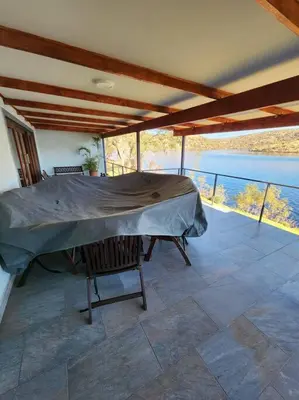 a covered porch with a table and a view of the water at Fish Eagle Bay View, Warmbaths in Bela-Bela