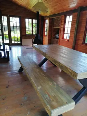 a large wooden table in a room with windows at Traveller's dream in Graskop