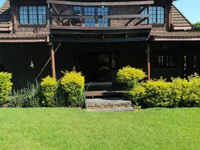 a black house with yellow bushes in front of it at Traveller's dream in Graskop