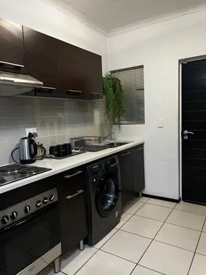 a kitchen with a washer and a stove and a dishwasher at A Stunning Cozy Apartment in Midrand