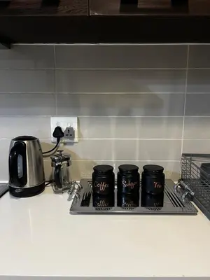 a tray with four black cups on a kitchen counter at A Stunning Cozy Apartment in Midrand