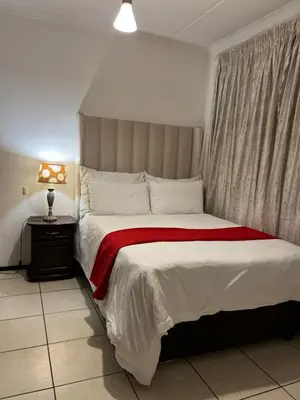 a bedroom with a large bed with a red blanket at A Stunning Cozy Apartment in Midrand