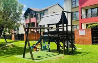 a park with a swing set in the grass at A Stunning Cozy Apartment in Midrand