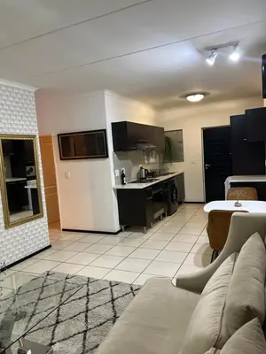 a living room with a couch and a kitchen at A Stunning Cozy Apartment in Midrand