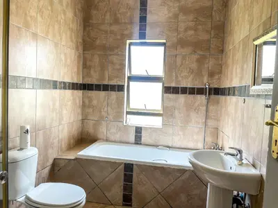 a bathroom with a tub and a toilet and a sink at Bobisemo Luxury Pretoria East Apartment in Tierpoort