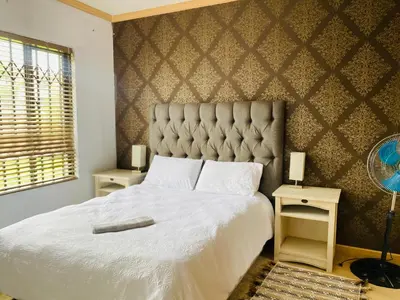 a bedroom with a large bed and two night stands at Siena Sun Apartment 10 in Midrand