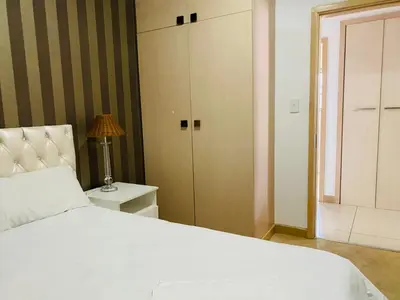 a bedroom with a white bed and a closet at Siena Sun Apartment 10 in Midrand