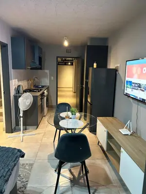 a living room with a table and a kitchen at Circa Apartment 86 in Pretoria