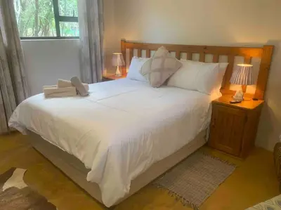 a bedroom with a large white bed with two lamps at Vlakkieskraal FarmStay - Bosvark Cabin in Bela-Bela