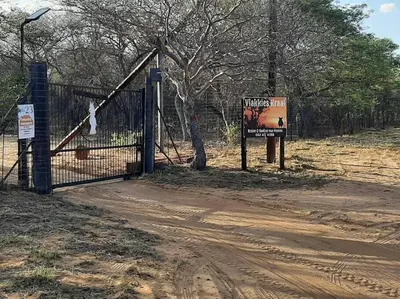 a fence with a sign next to a dirt road at Vlakkieskraal FarmStay - Bosvark Cabin in Bela-Bela