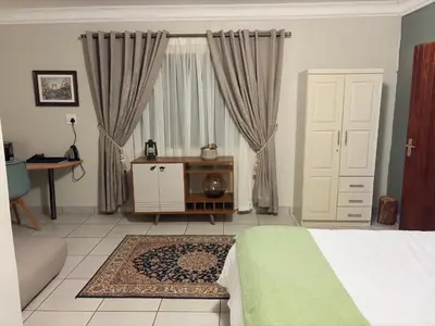 a bedroom with a bed and a table and a window at Private room Skyfall Country Estate in Polokwane