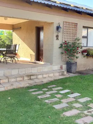 a porch of a house with a bench in the grass at Private room Skyfall Country Estate in Polokwane