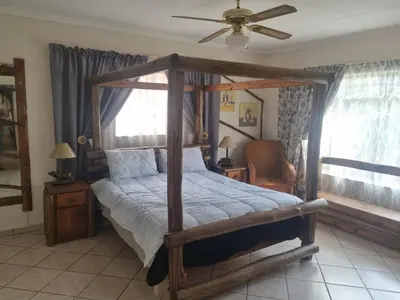 a bedroom with a canopy bed and a chair at Bosveld Kuier Hoofhuis in Bela-Bela