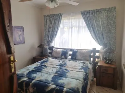 a bedroom with a bed and a window with curtains at Bosveld Kuier Hoofhuis in Bela-Bela