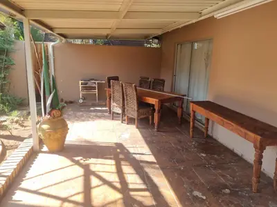 a patio with a wooden table and chairs at Bosveld Kuier Hoofhuis in Bela-Bela