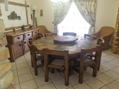 a dining room with a wooden table and chairs at Bosveld Kuier Hoofhuis in Bela-Bela