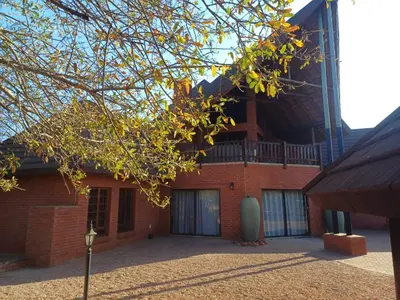a red brick building with a tree in front of it at Makhato Bush Lodge 6 in Bela-Bela