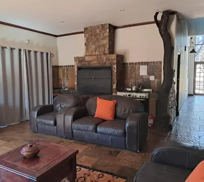 a living room with a leather couch and a fireplace at Makhato Bush Lodge 6 in Bela-Bela