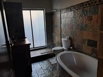 a bathroom with a tub and a toilet and a window at Makhato Bush Lodge 6 in Bela-Bela