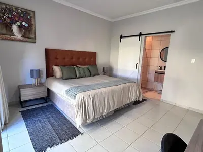 a bedroom with a large bed and a shower at Winterfell Lephalale Lodge in Lephalale