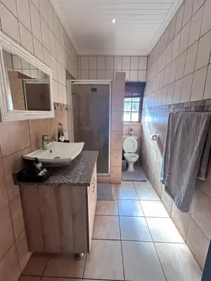 a bathroom with a sink and a shower and a toilet at Winterfell Lephalale Lodge in Lephalale