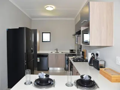 a kitchen with a black refrigerator and a white counter top at Elcaro Luxury Villas - The View in Midrand