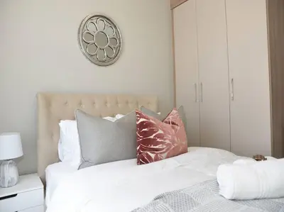 a white bed with pillows and a clock on the wall at Elcaro Luxury Villas - The View in Midrand