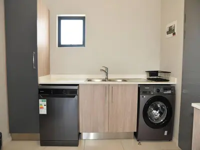 a kitchen with a sink and a washing machine at Elcaro Luxury Villas - The View in Midrand