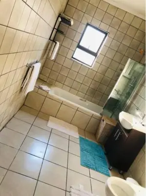 a bathroom with a tub and a toilet and a window at Serenity Cottage in Benoni