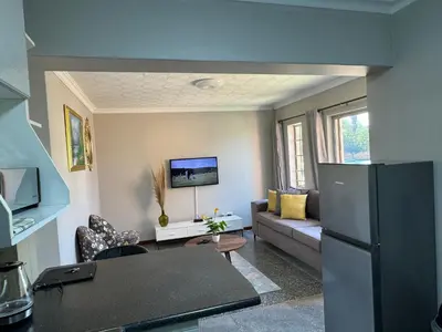 a living room with a couch and a refrigerator at ATHA AirBnB in Midrand