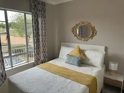 a bedroom with a bed with a mirror and a window at ATHA AirBnB in Midrand