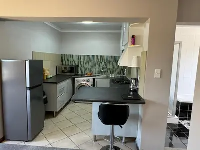 a kitchen with a refrigerator and a table in it at ATHA AirBnB in Midrand