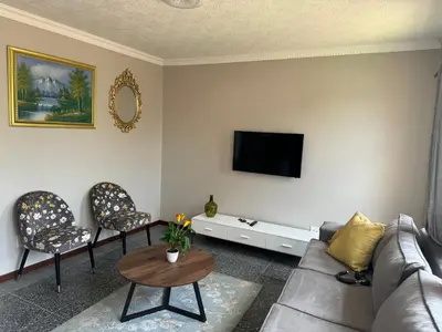 a living room with a couch and chairs and a tv at ATHA AirBnB in Midrand