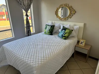 a bedroom with a white bed with pillows and a mirror at ATHA AirBnB in Midrand