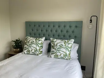 a bed with a green headboard and two pillows at The Blyde Stylish Homes in Pretoria