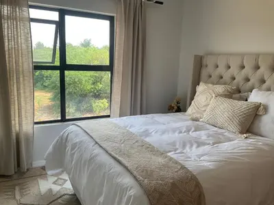 a bed in a bedroom with a large window at The Blyde Stylish Homes in Pretoria