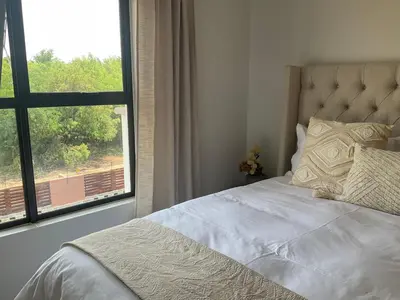 a bedroom with a bed and a large window at The Blyde Stylish Homes in Pretoria