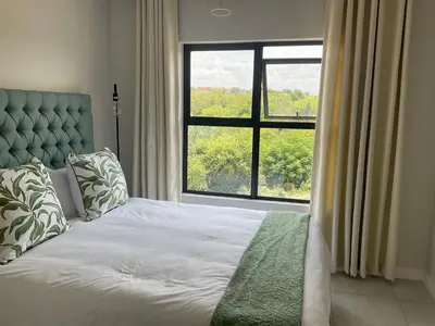 a bedroom with a bed with a large window at The Blyde Stylish Homes in Pretoria