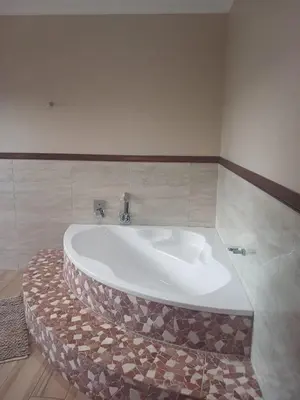 a bath tub in a bathroom with a tile wall at Zebula Golf and Wildlife Estate - Moi Signature Exclusive Leisure Villas in Mabula
