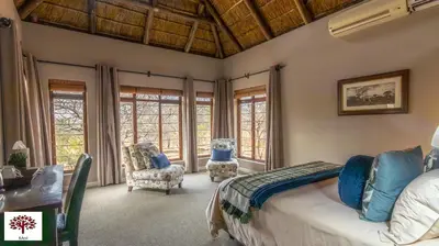 a bedroom with a bed and a desk and windows at Zebula Golf and Wildlife Estate - Moi Signature Exclusive Leisure Villas in Mabula
