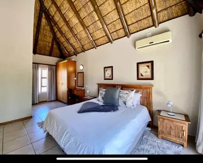 a bedroom with a large bed with a wooden headboard at Zebula Golf and Wildlife Estate - Moi Signature Exclusive Leisure Villas in Mabula