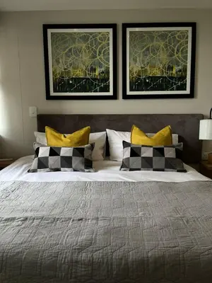 a bedroom with a large bed with two pictures on the wall at REGENCY APARTMENT HOTEL-ST@Y in Pretoria
