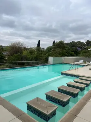 a large swimming pool with blue water and chairs at REGENCY APARTMENT HOTEL-ST@Y in Pretoria