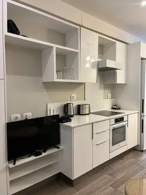 a kitchen with white cabinets and a flat screen tv at REGENCY APARTMENT HOTEL-ST@Y in Pretoria
