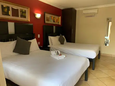 two beds in a hotel room with white sheets at Ivory Lodge Bendor in Polokwane
